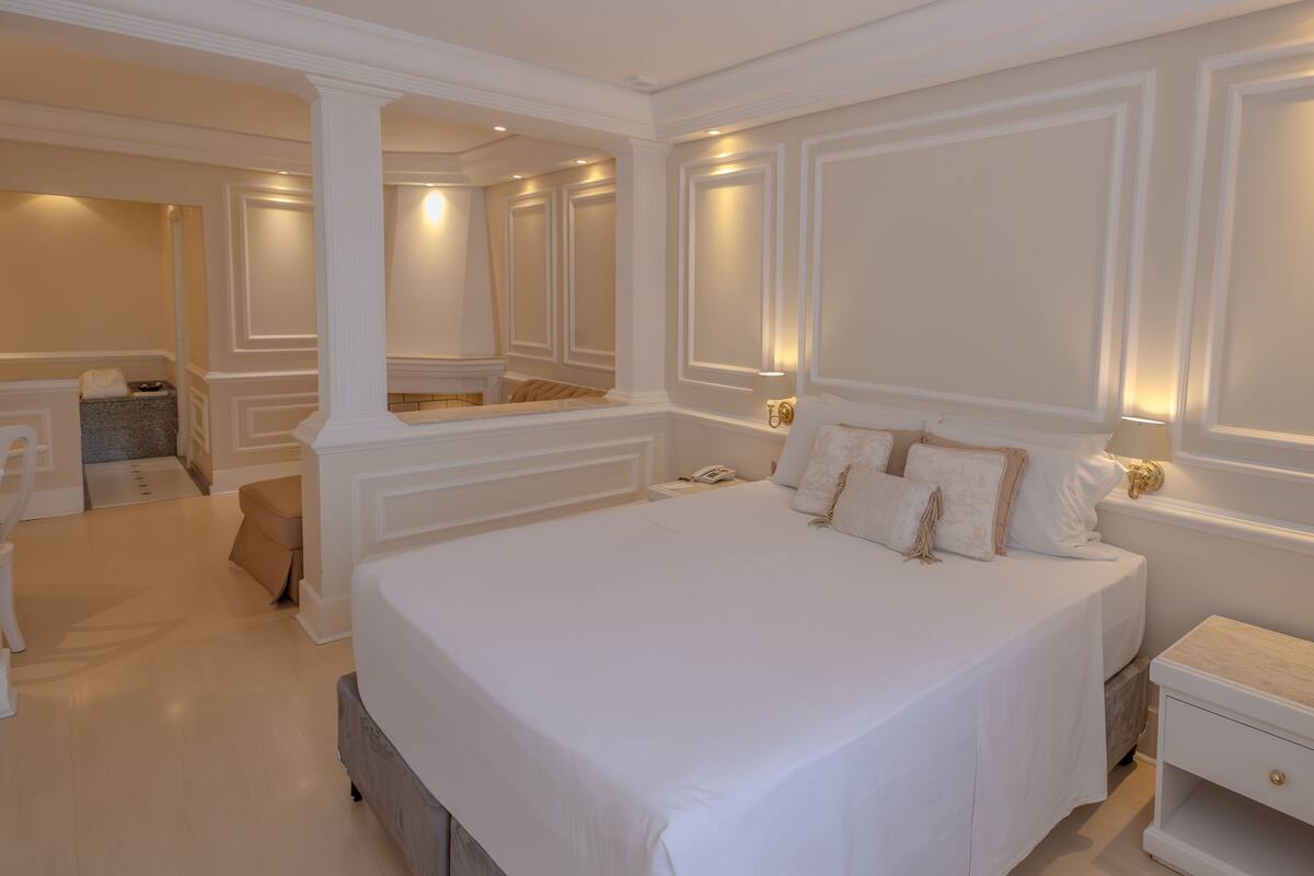 A spacious bedroom with a large bed, a bedside table, a nightstand, and a built-in wardrobe.