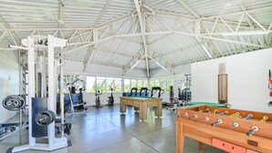 A gym with exercise equipment, a pool table, and a foosball table.