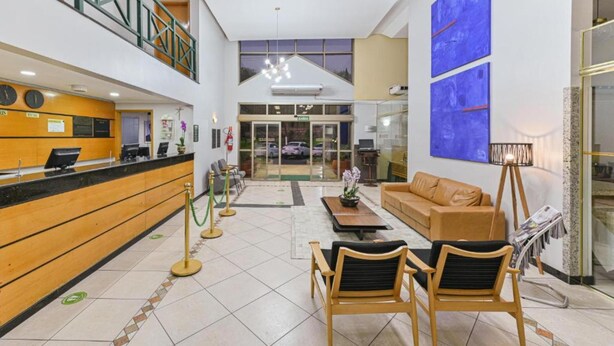 A hotel lobby with a reception desk, seating area, and a staircase.