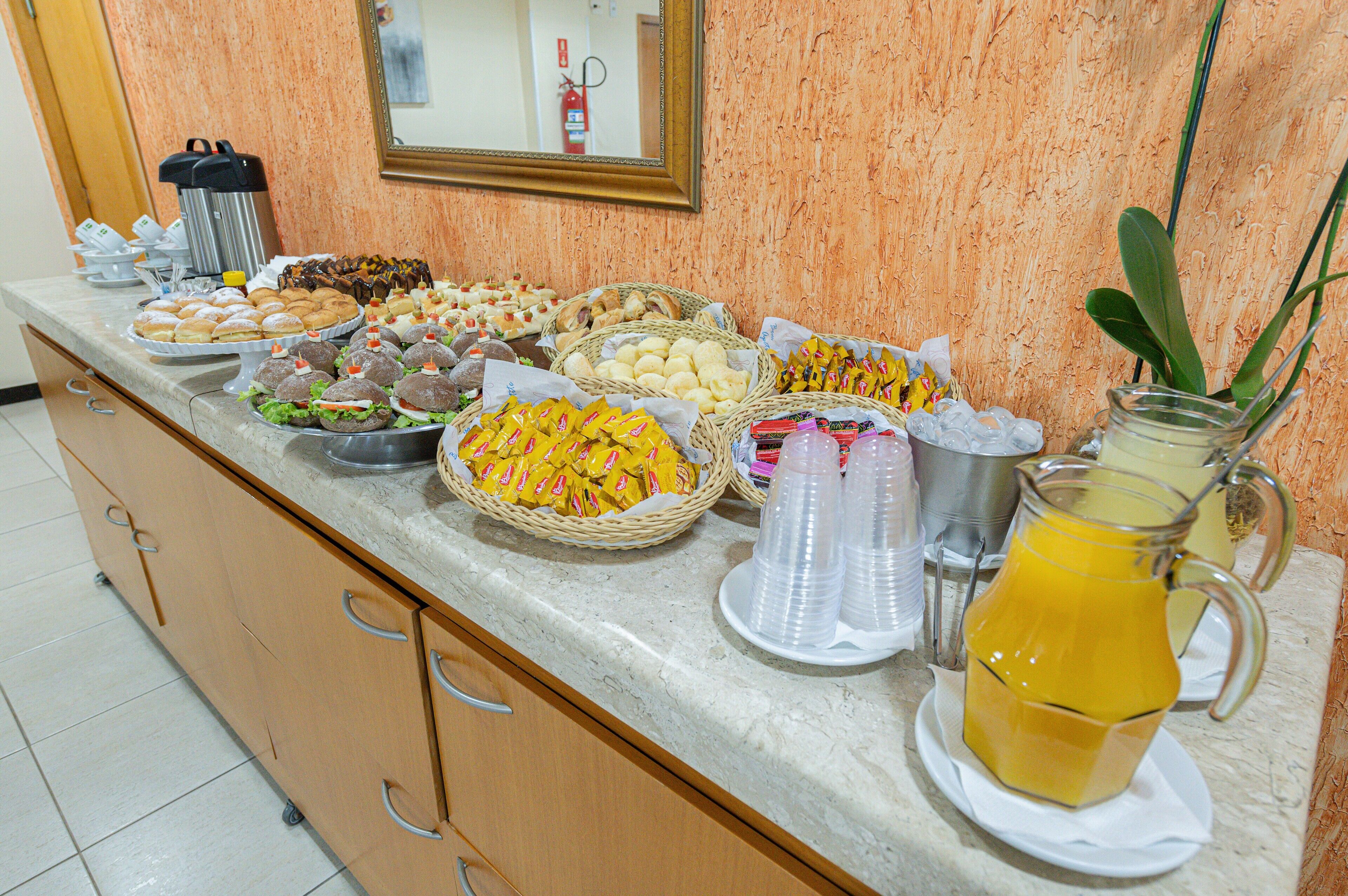 A buffet spread with various food items and a pitcher of orange juice.