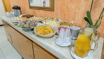 A buffet spread with various food items and a pitcher of orange juice.