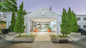 A hotel entrance with a covered walkway, potted plants, and a clear view of the interior.