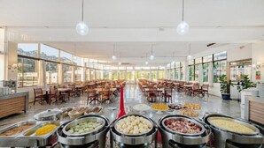 A buffet with various food items, a seating area with tables and chairs, and large windows providing natural light.