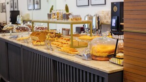 A buffet counter with various food items displayed in glass containers and trays. - Metropolitan Hotel (Teresina)