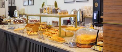 Un mostrador de buffet con diversos alimentos exhibidos en recipientes y bandejas de vidrio.