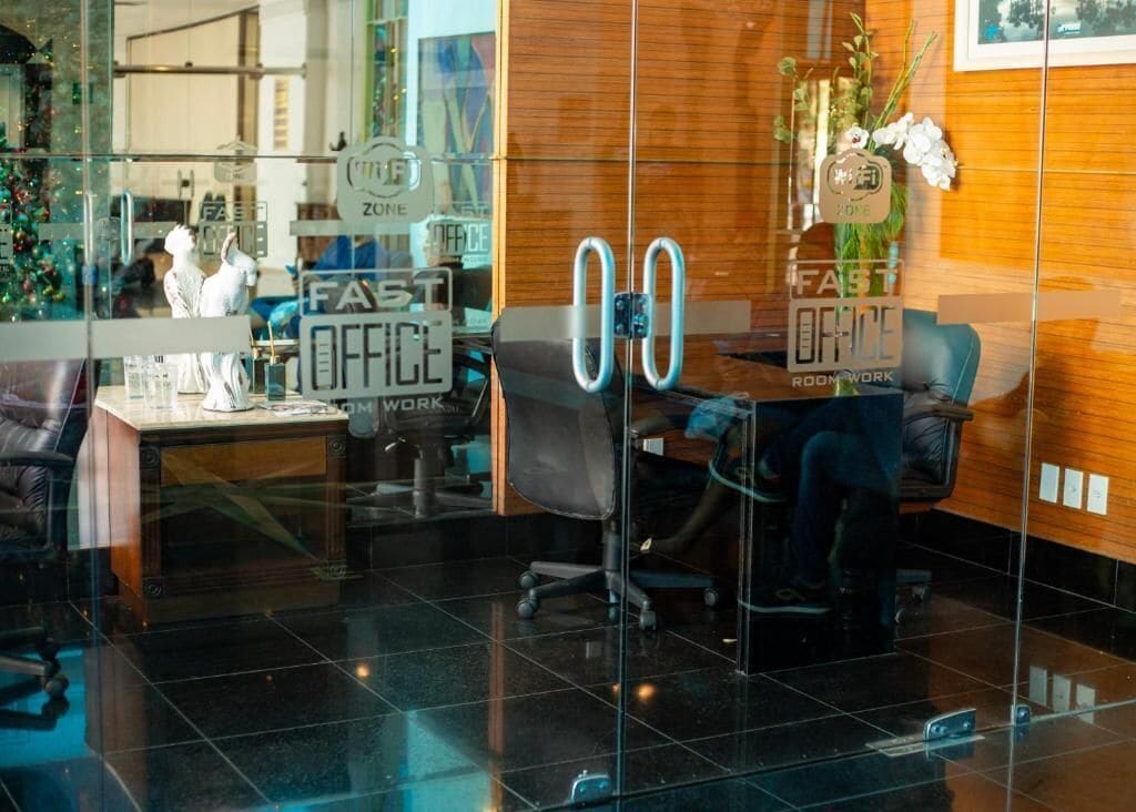 An office space with glass partitions, a reception desk, and a sign that reads 'FAST OFFICE.'