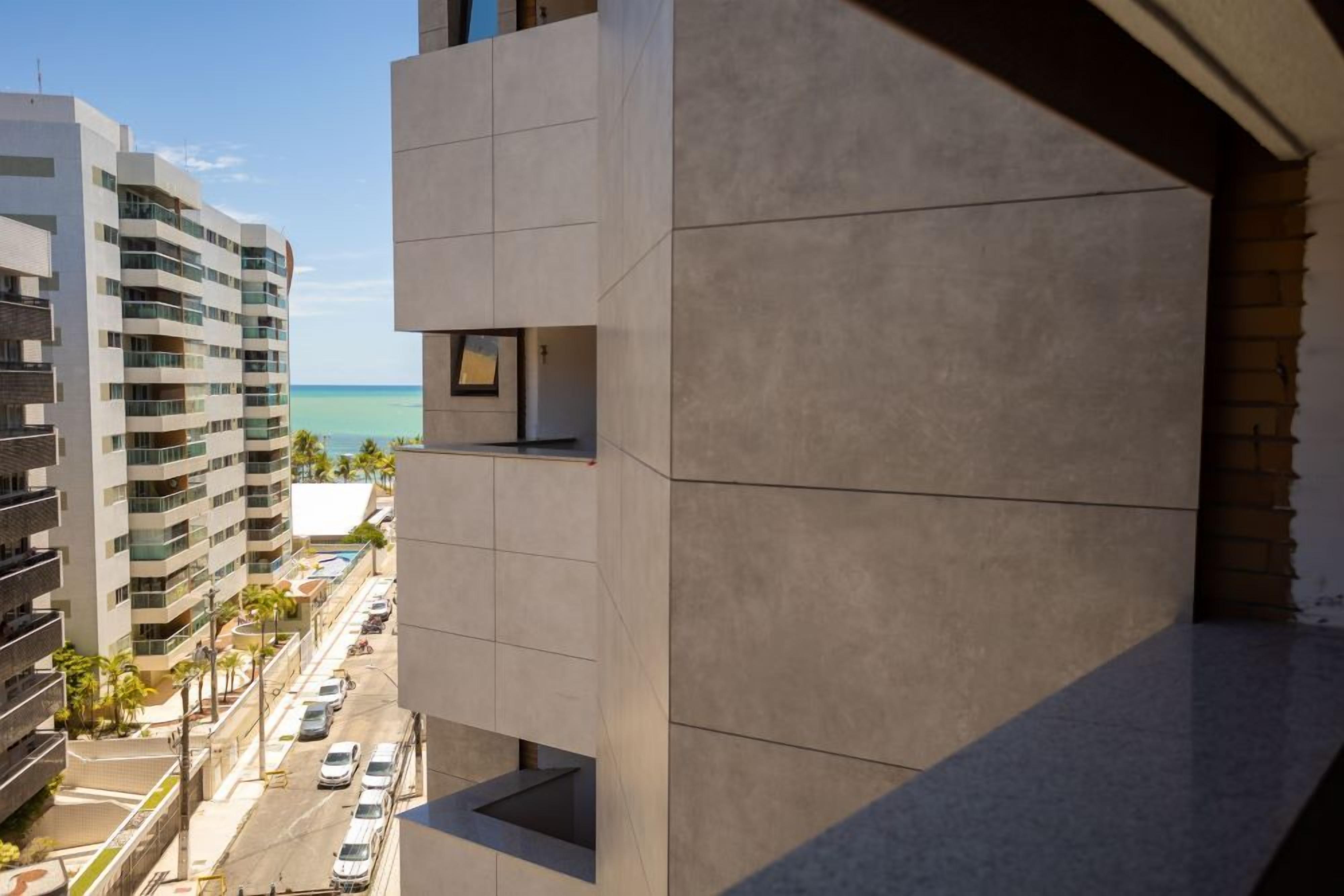 A modern building with a view of the ocean and parked cars.