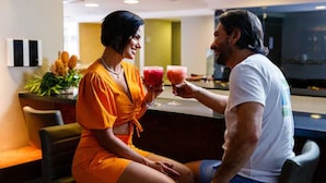 Una pareja sentada en un bar dentro del moderno vestíbulo de un hotel, con barra y zona de estar.