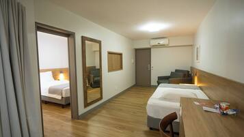 A hotel room with two beds, a desk, a chair, a wardrobe, and a mirror.