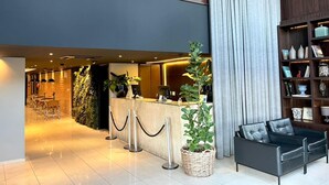 A modern lobby with a reception desk, seating area, and a large window. - Oasis Tower Hotel (Ribeirão Preto)