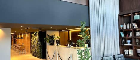A modern lobby with a reception desk, seating area, and a large window.