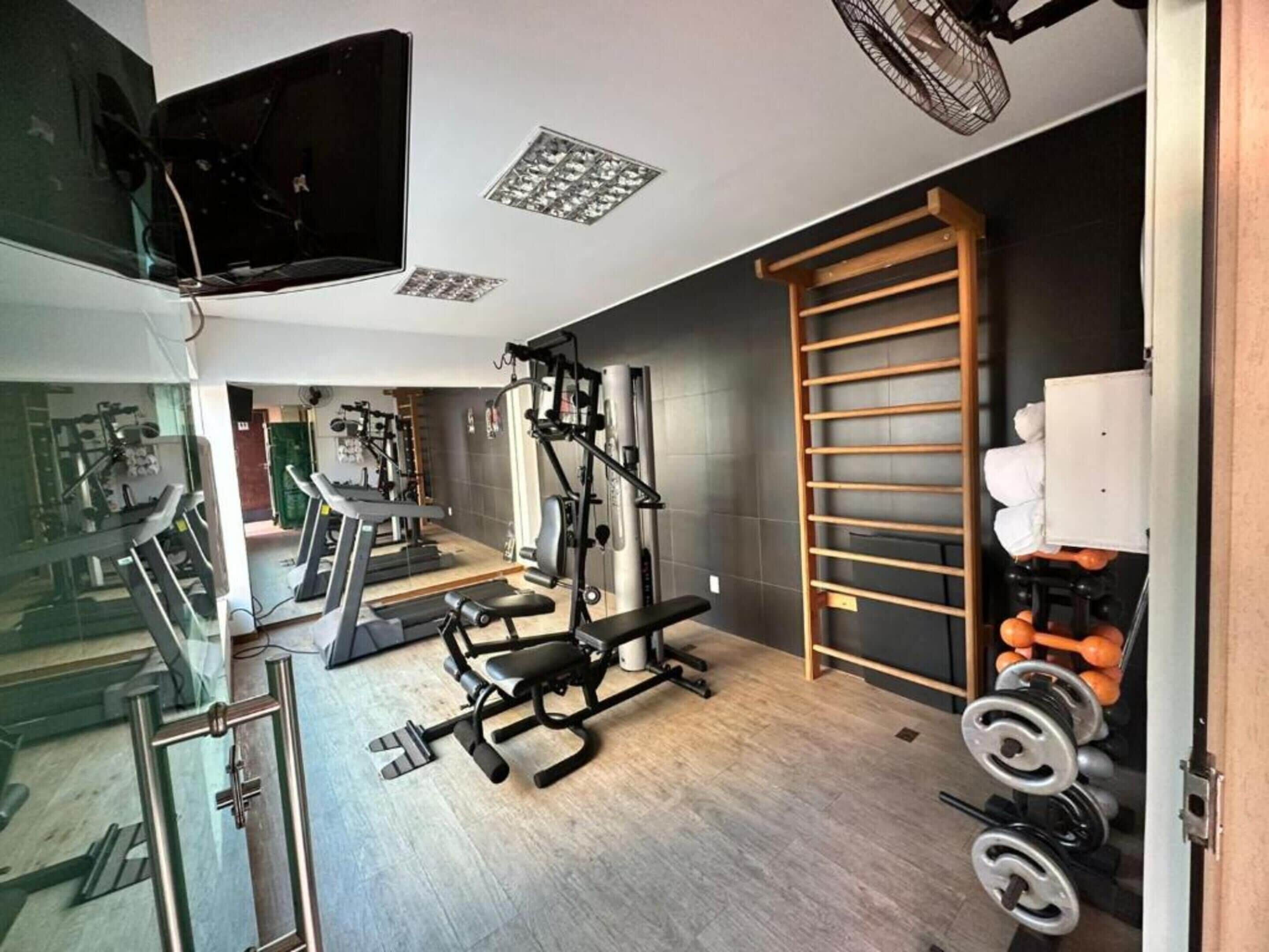 A gym with exercise equipment, a TV, and a wooden ladder.
