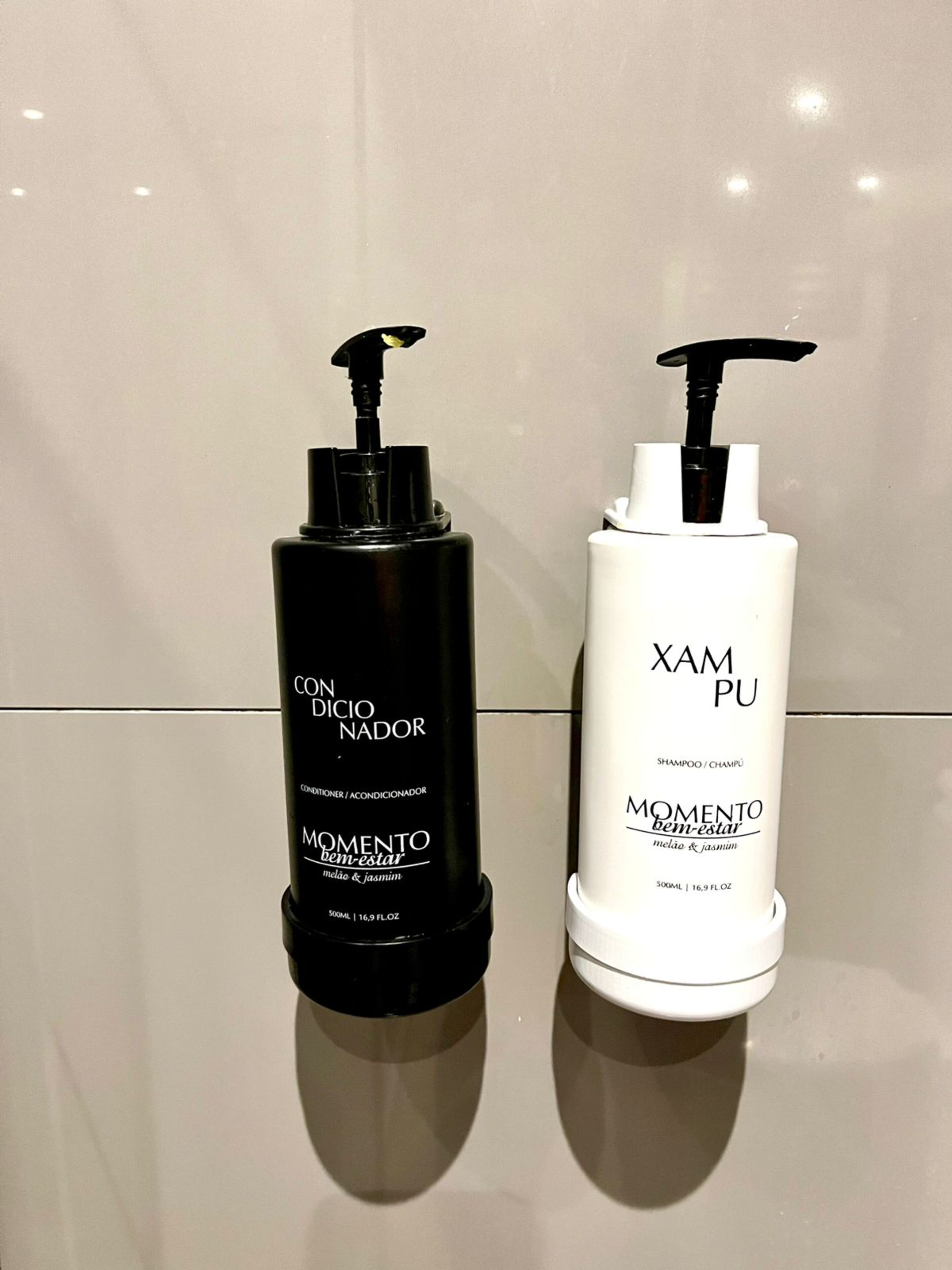 Two bottles of shampoo on a reflective surface.