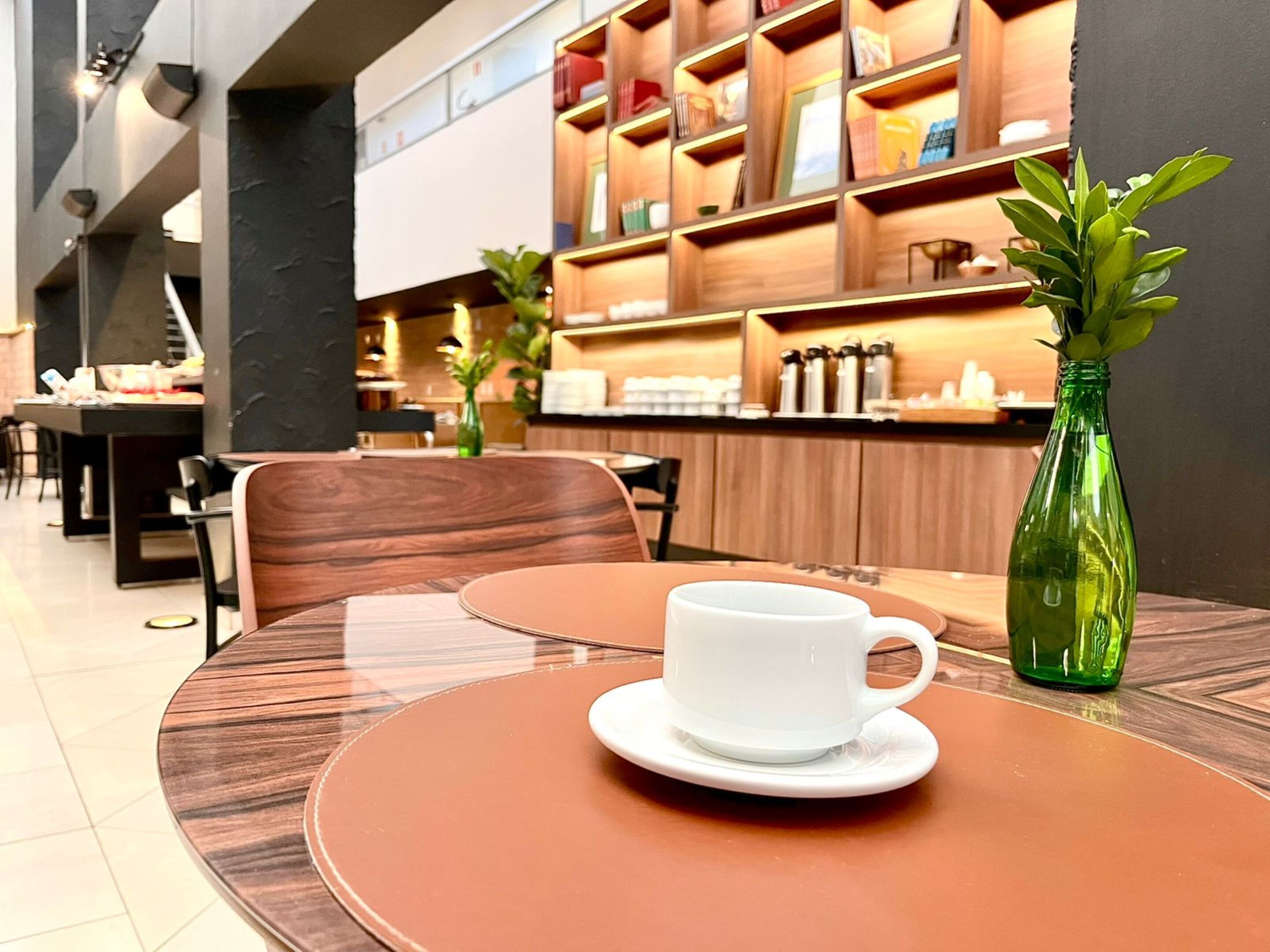 A modern interior with a round table, a white cup, and a green bottle on the table.