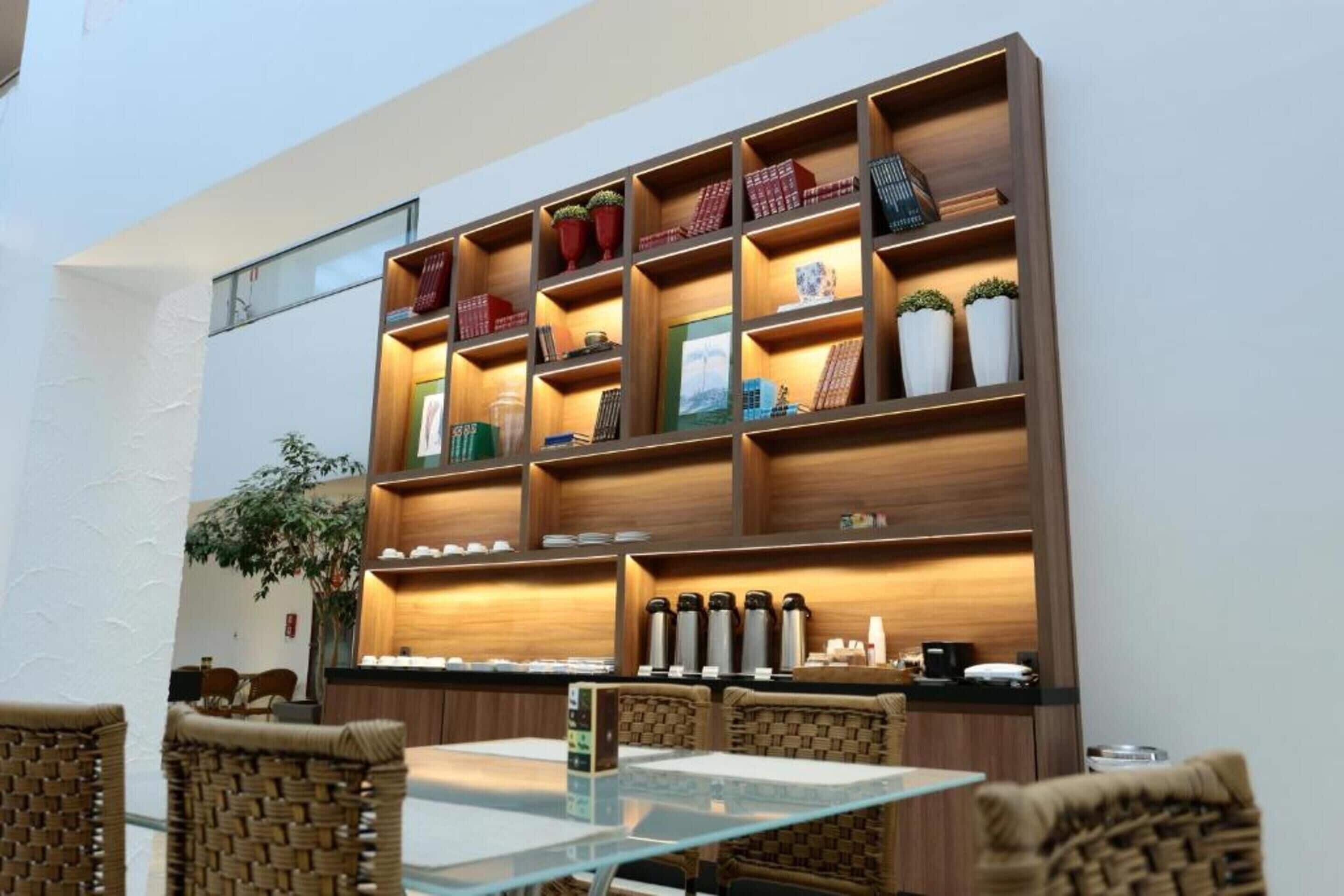 A modern interior with a wooden bookshelf, wicker chairs, and a glass table.