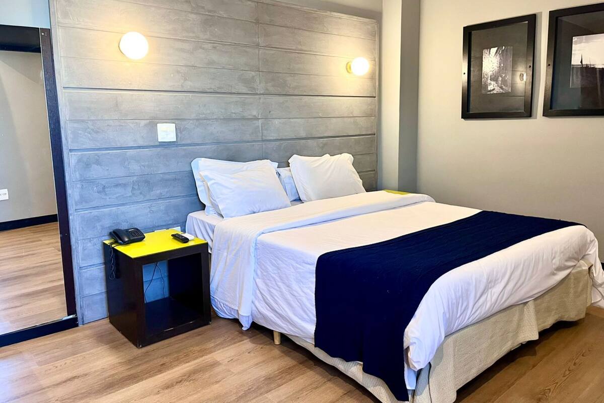 Camera d'albergo con un letto grande, un comodino con un telefono e due luci a parete.