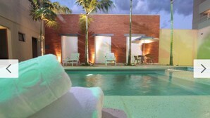 A pool area with lounge chairs, a brick building, and palm trees. - Oasis Tower Hotel (Ribeirão Preto)