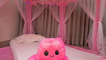 Relax in a serene space with a plush pink bed, adorned with a whimsical octopus-shaped pillow and sheer curtains.