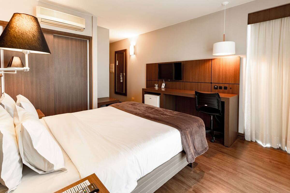 Une chambre d’hôtel équipée d’un lit, d’un bureau, d’une télévision et d’une lampe.