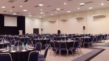 Un amplio salón de conferencias con filas de mesas y sillas, equipado con botellas de agua y tarjetas de identificación.