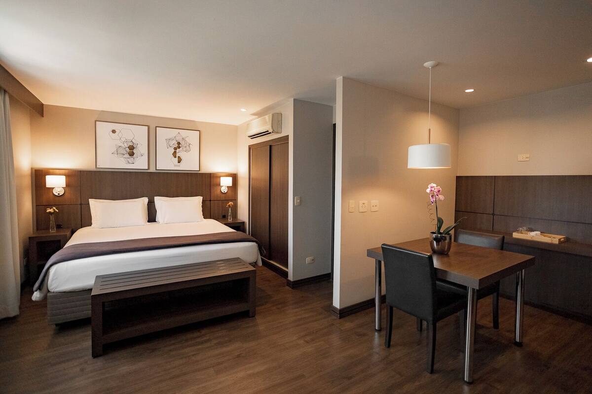 Une chambre d’hôtel moderne équipée d’un lit, de tables de chevet, d’un bureau et d’une chaise.