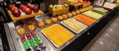 Un bufé con frutas, verduras y bebidas variadas.