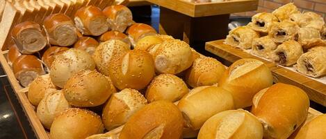 Una variedad de panes y pasteles expuestos en bandejas de madera.