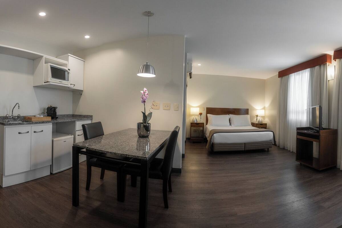 Une chambre d’hôtel compacte comprenant un coin cuisine, un lit, un canapé et un espace repas.