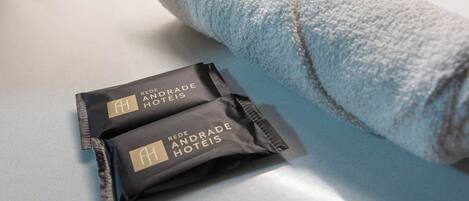 Two packages labeled "Rede Andrade Hotéis" on a white surface next to a rolled towel.