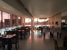 Un'ampia sala da pranzo con soffitti alti, grandi finestre che offrono vista sulla città e un arredamento moderno.