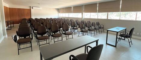 A conference room with rows of chairs and tables, large windows, and a neutral color scheme.