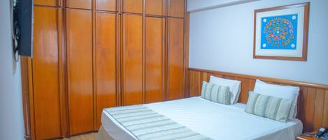 Un dormitorio con una cama grande, un armario de madera y un cuadro enmarcado en la pared.