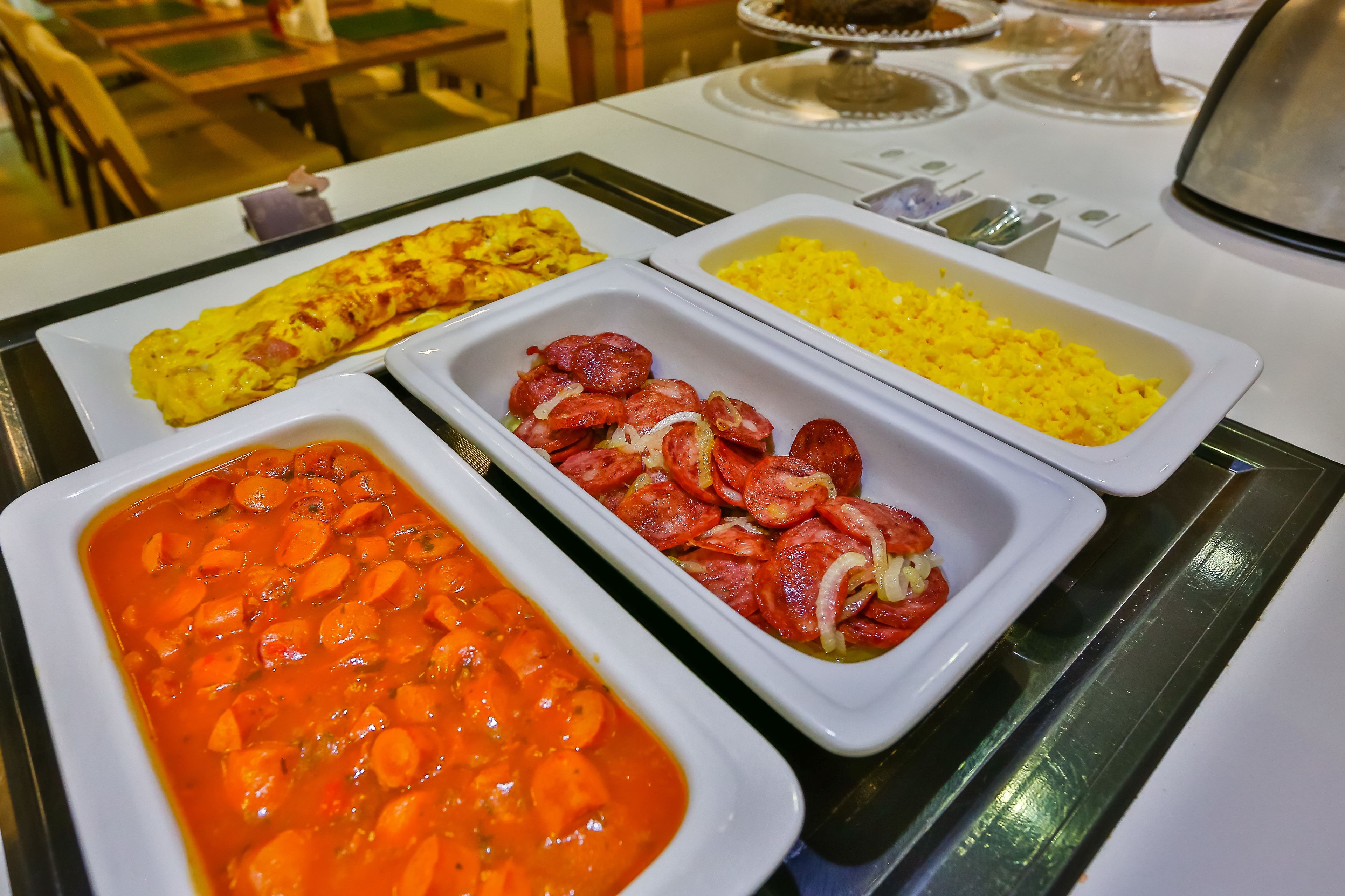 A buffet with various dishes including omelettes, rice, and a vegetable stew.