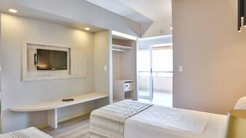 A modern hotel room with a bed, a desk, a TV, a closet, and a balcony.