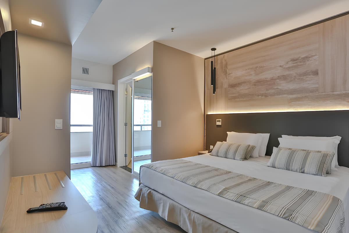 Une chambre d’hôtel moderne dotée d’un grand lit, d’un téléviseur à écran plat et offrant une vue sur l’extérieur.