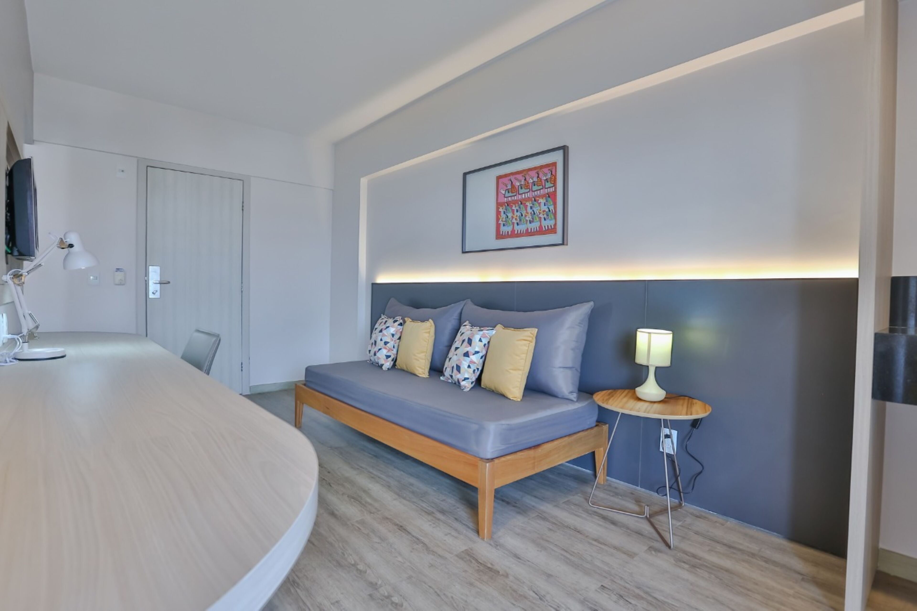 A modern room with a sofa, a small table, a lamp, and a framed picture on the wall.