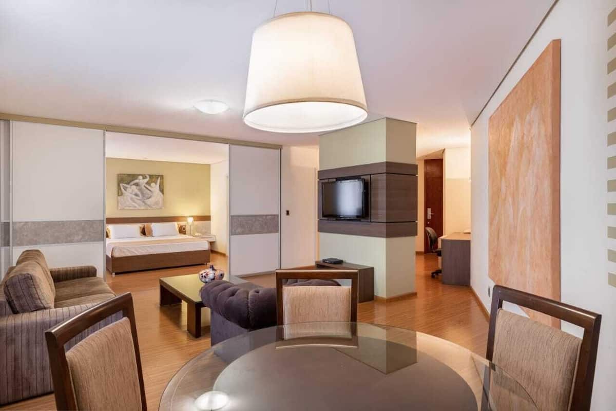 Ett modernt hotellrum med en soffa, ett matbord, en TV och en stor tavla på väggen.