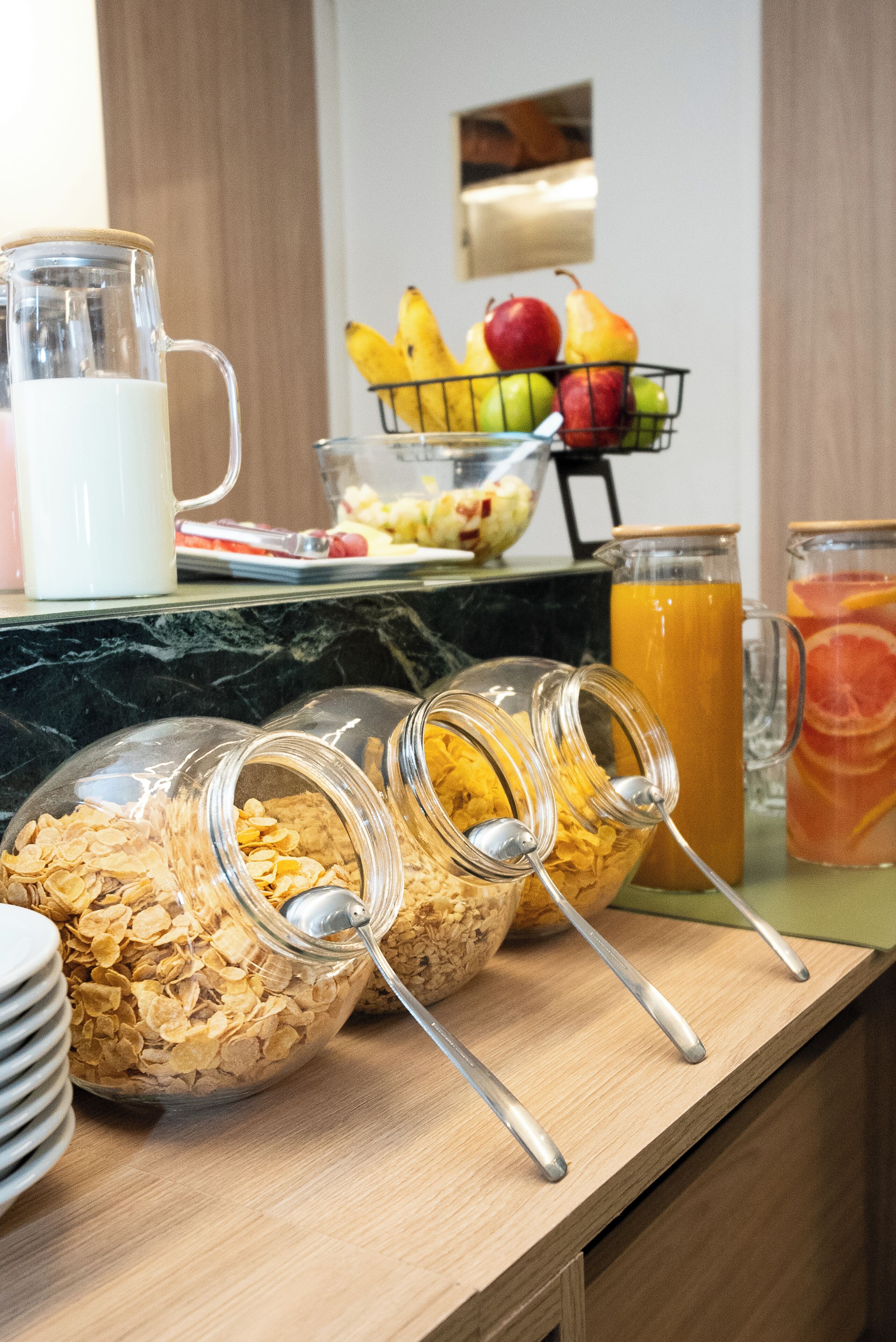 Un bufé de desayuno con cereales, frutas y bebidas.
