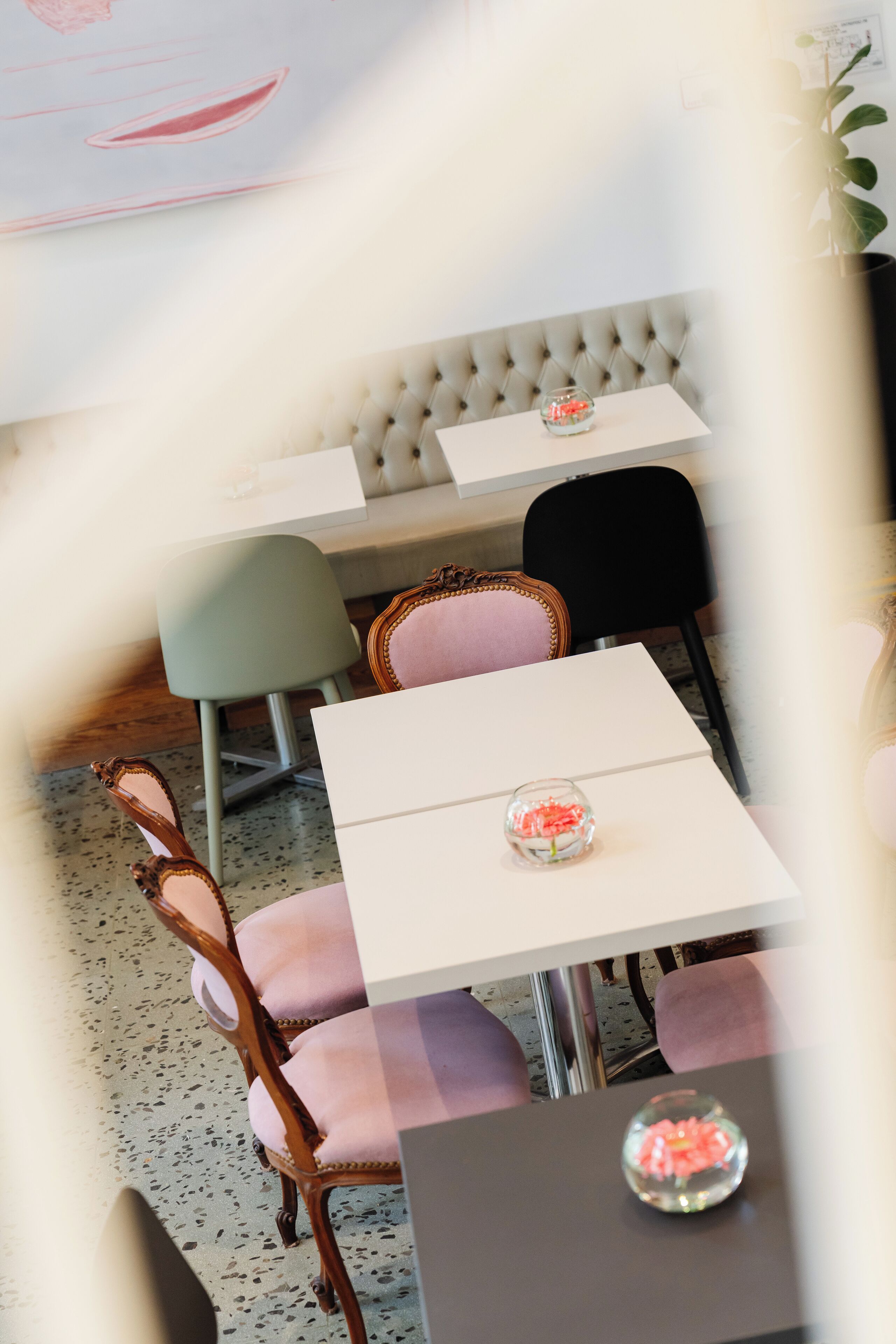Zona pranzo con una testiera trapuntata, un tavolo bianco e una ciotola di vetro con elementi rossi.