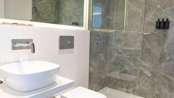 A modern bathroom with a white sink, toilet, and glass-enclosed shower.