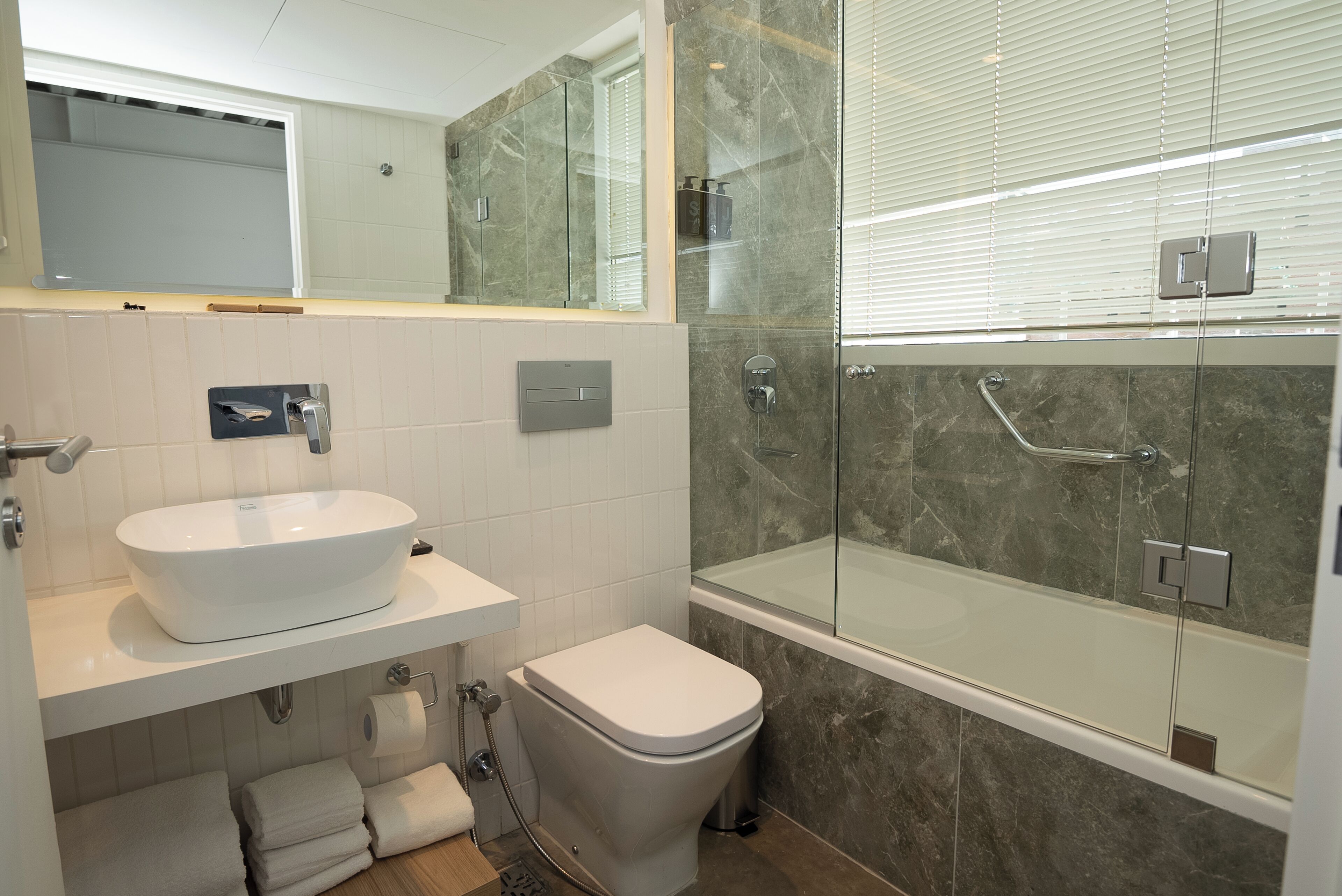 A modern bathroom with a white sink, toilet, and glass-enclosed shower.