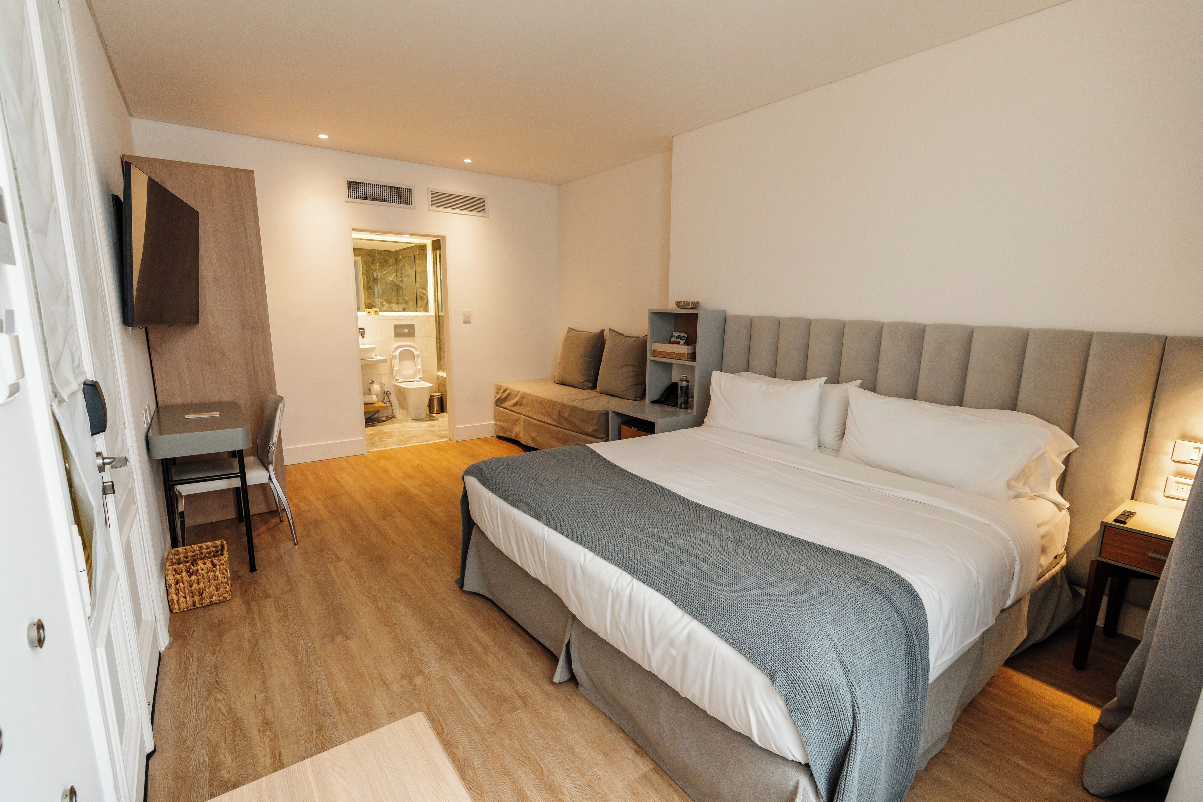 A modern bedroom with a large bed, bedside tables, a desk, and a wardrobe.