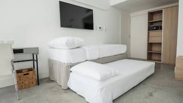 A modern bedroom with a bed, a TV mounted on the wall, a wooden wardrobe, and a small table with a basket underneath.