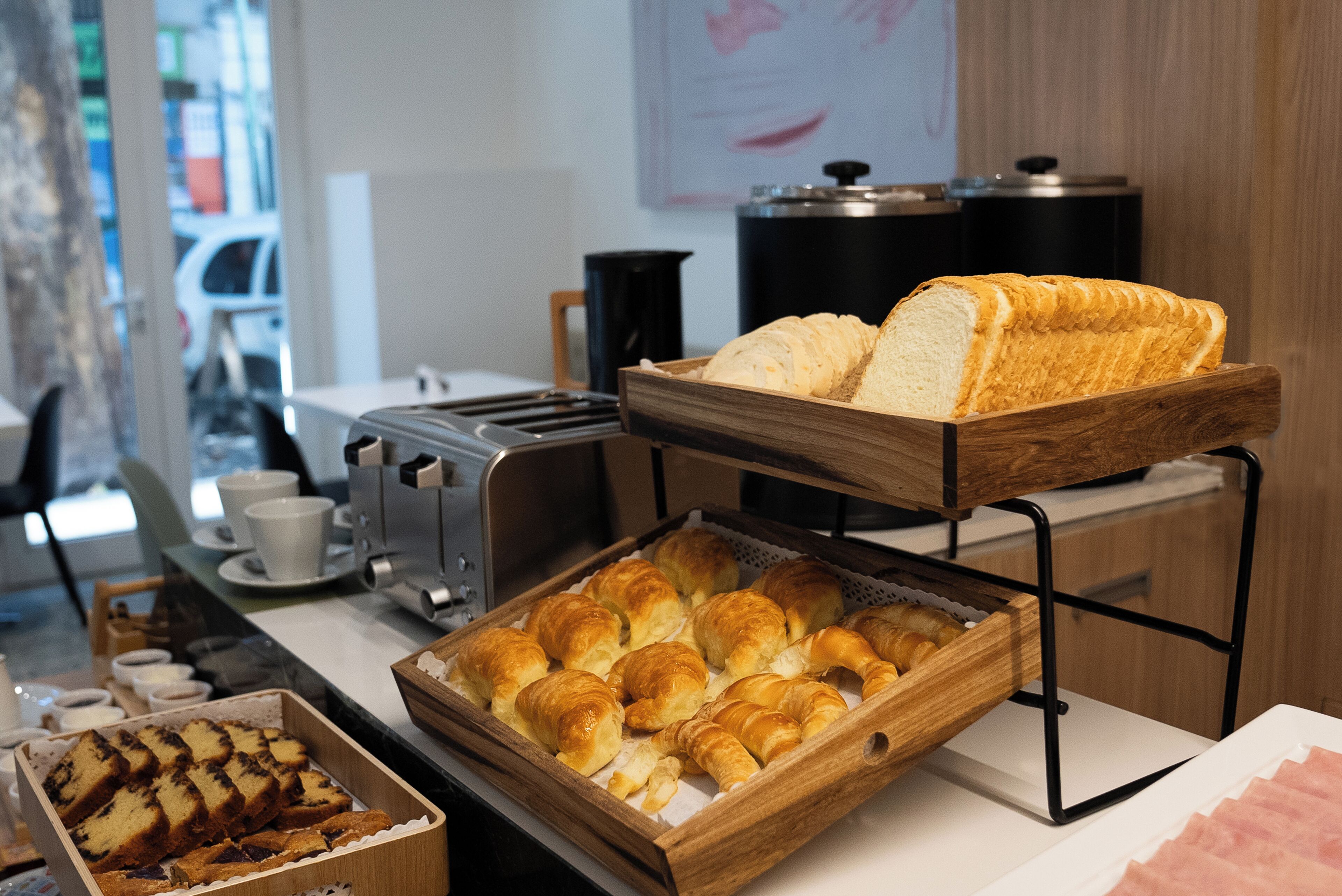 Un bufé de desayuno con pan, bollería y café.