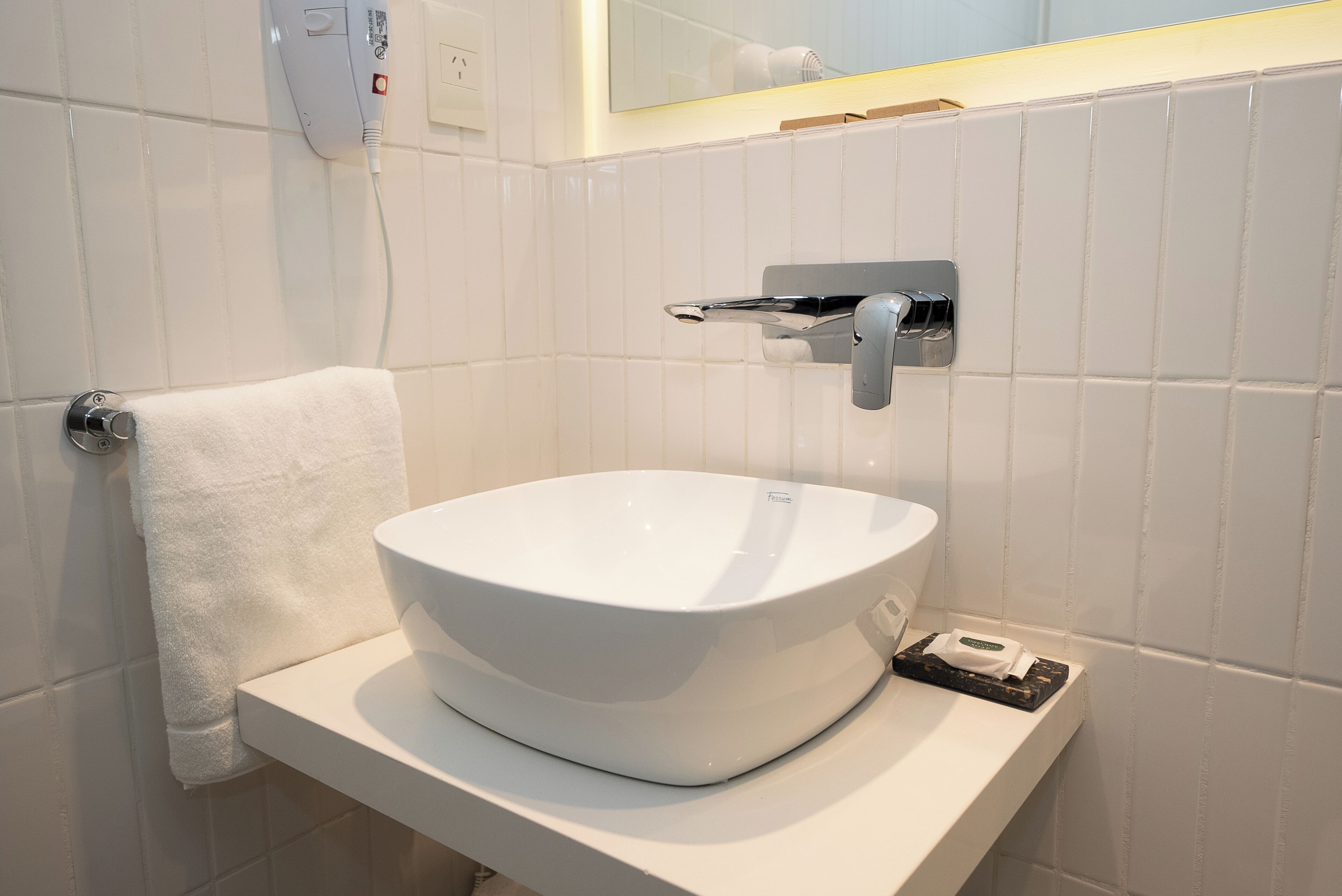 A bathroom with a white sink, towel rack, and a mirror.