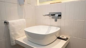 Un bagno con un lavandino bianco, un portasciuga e uno specchio.