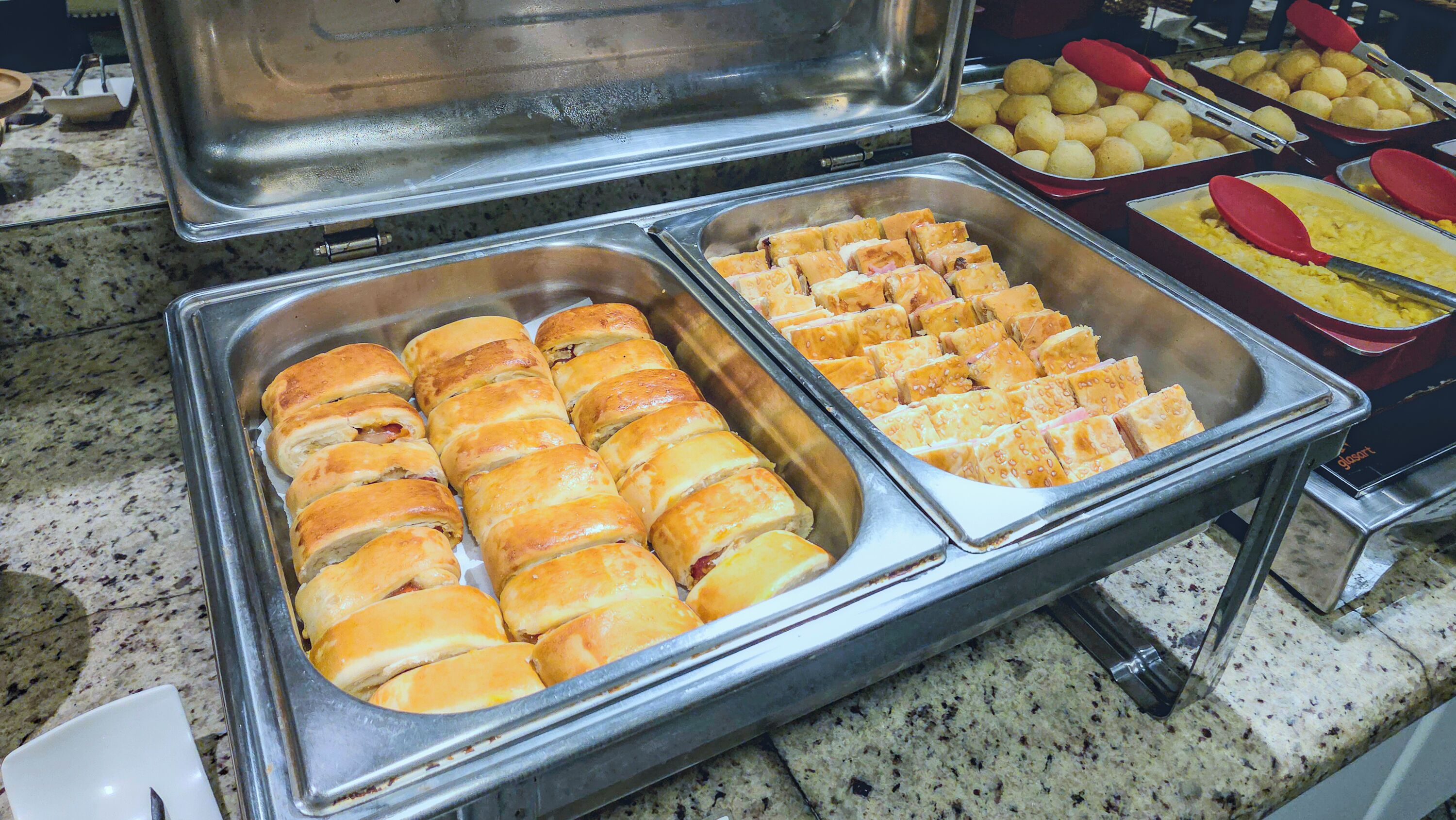 A buffet with various food items including pastries and potatoes.