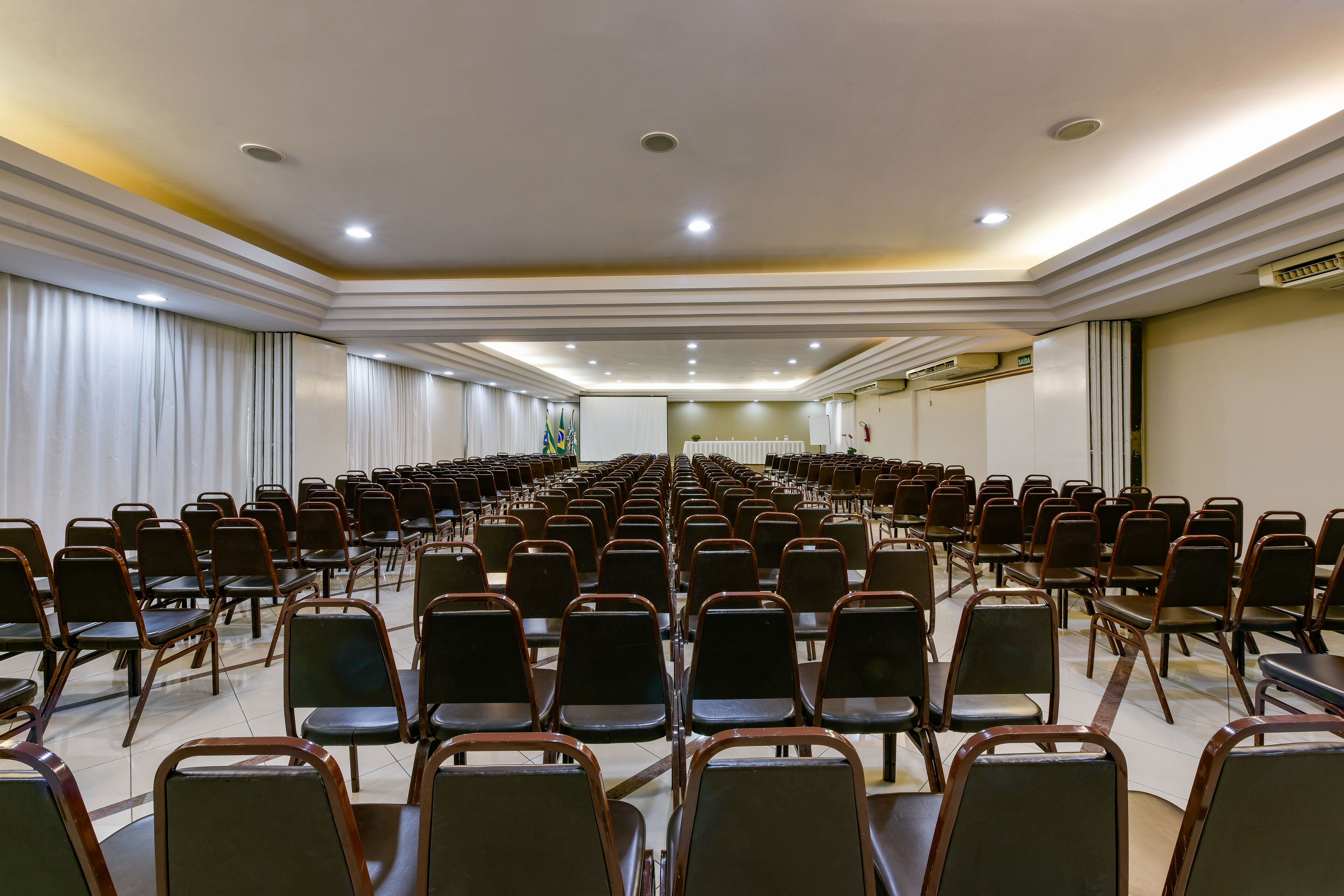 Ein Konferenzraum mit Reihen von Stühlen, einer Bühne und einem Rednerpult.