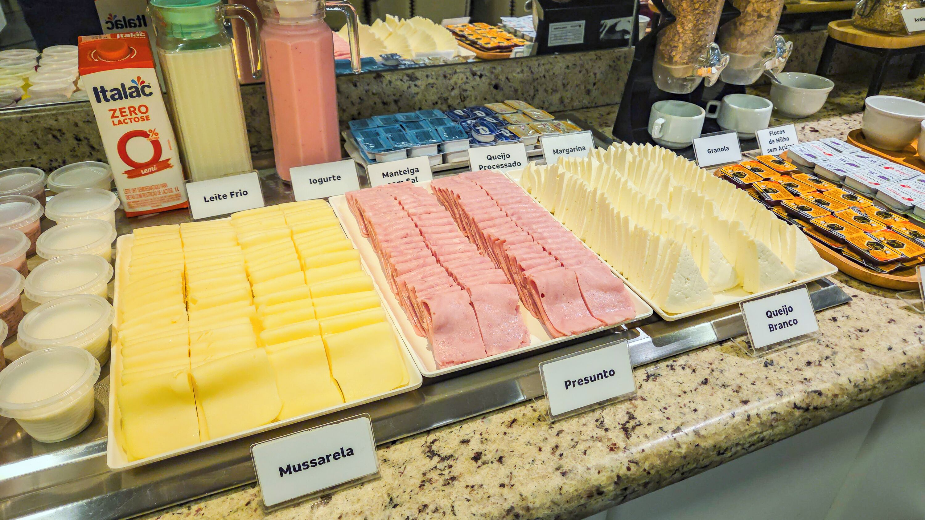 A buffet with various food items including cheese, processed cheese, and different types of meat.