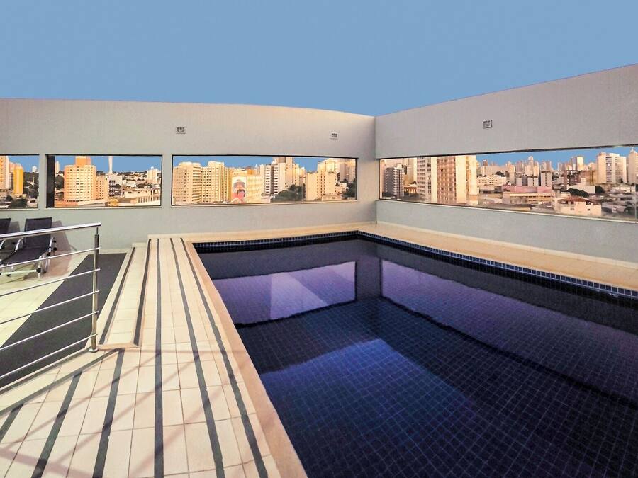 Une piscine sur le toit offrant une vue sur la ville, un espace salon et une terrasse carrelée.
